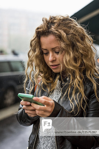 Frau auf der Straße schaut auf Smartphone