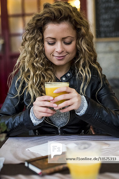 Frau im Café trinkt Orangensaft