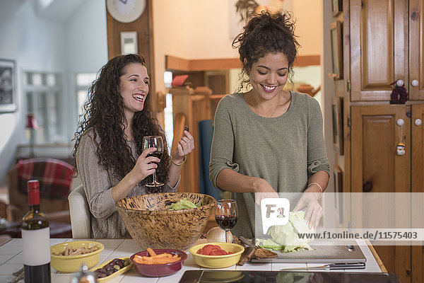Zwei Freundinnen bereiten Salat an der Küchentheke zu