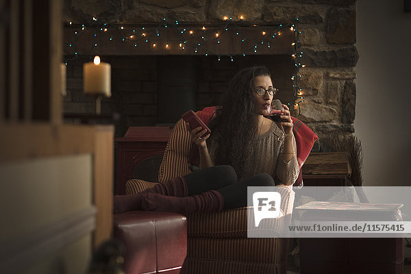 Junge Frau entspannt sich im Sessel und trinkt Rotwein