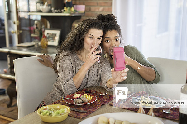Zwei junge Freundinnen nehmen Selbstgefälligkeit beim Rotweintrinken am Küchentisch
