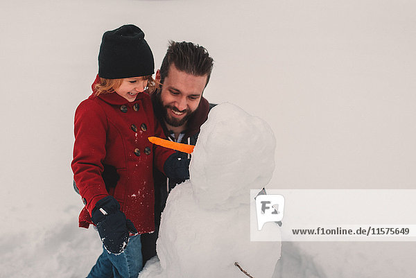 Father and daughter making snowman