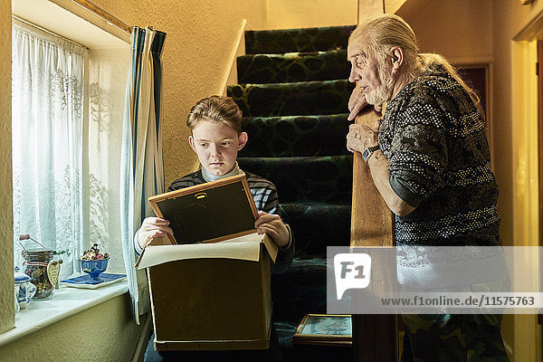 Älterer Mann erklärt seinem Enkel  der auf einer Treppe sitzt  mit einem Fotorahmen