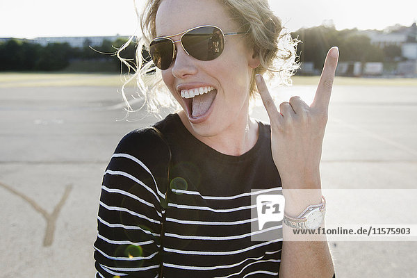 Porträt einer mittelgroßen erwachsenen Frau mit Sonnenbrille  die eine Handbewegung macht