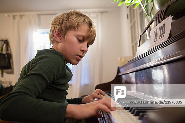 Junge spielt Klavier im Wohnzimmer