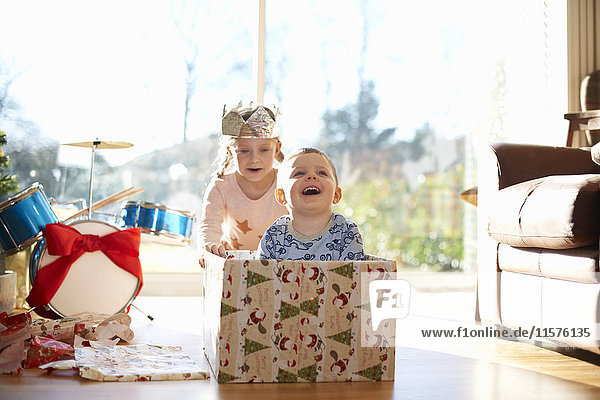 Mädchen schiebt Bruder in Pappkarton zu Weihnachten