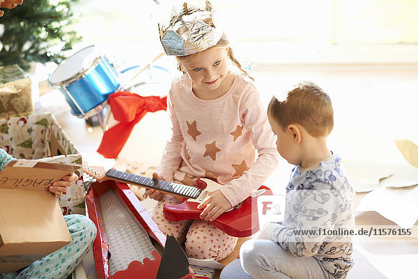 Mädchen und Bruder spielen am Weihnachtstag mit Spielzeuggitarre