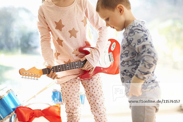Mädchen und Bruder spielen am Weihnachtstag mit Spielzeuggitarre