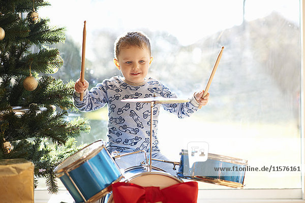 Junge spielt Spielzeug-Schlagzeug am Weihnachtstag