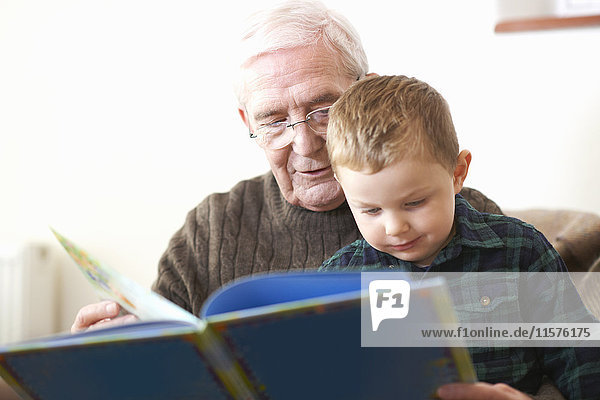 Älterer Mann liest Enkel Buch vor
