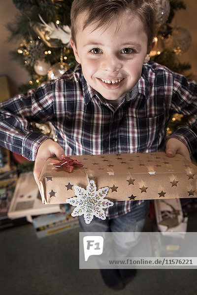 Porträt eines Jungen,  der ein Weihnachtsgeschenk überreicht