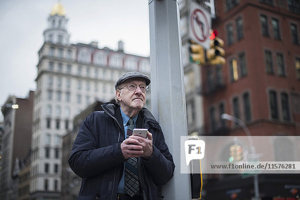 Mann lehnt an Laternenpfahl und hält Smartphone  Manhattan  New York  USA