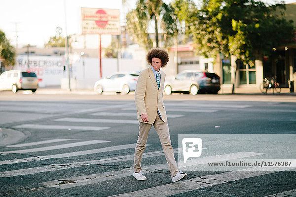 Teenage boy with red afro hair  wearing suit  on pedestrian crossing