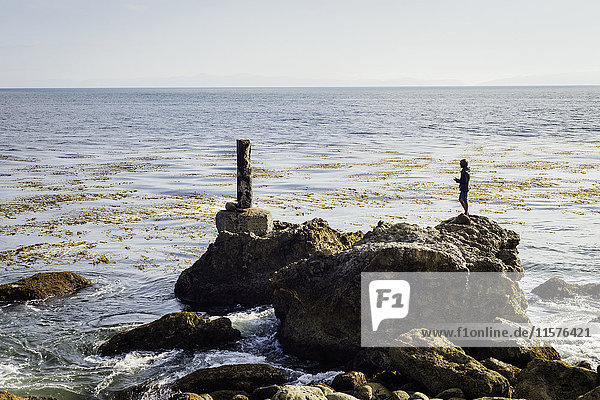 Mature man  standing on rocks by sea  looking at view