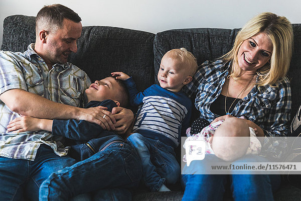 Family sitting on sofa young baby on mother's lap