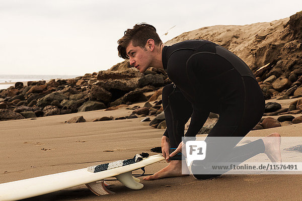 Young man on beach with surfboard  preparing to surf