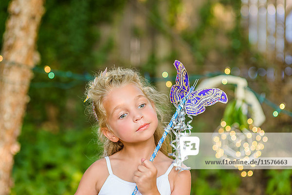 Portrait of young girl holding butterfly wand