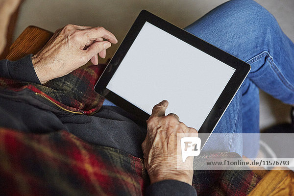 Senior woman sitting in chair  using digital tablet  elevated view