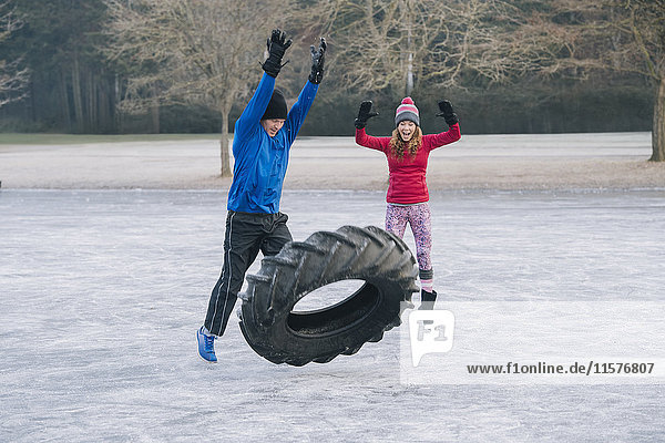 Couple flipping tyre on frozen lake