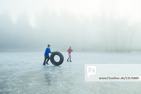 Mann rollt Reifen auf gefrorenem See