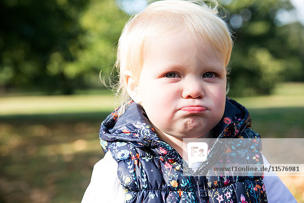 Portrait eines weiblichen Kleinkindes mit schmollender Lippe im Park