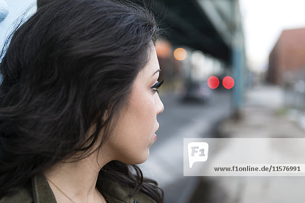 Profile portrait of young woman in city looking over her shoulder