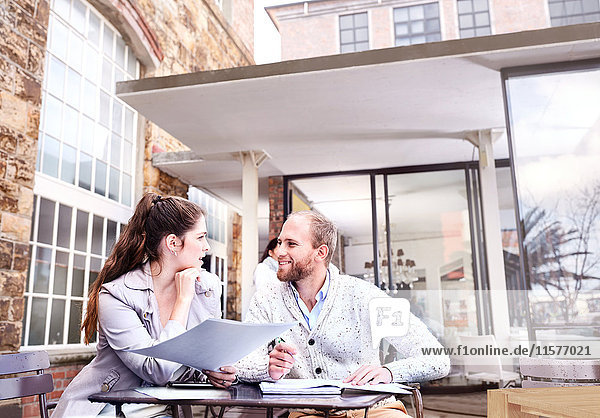 Geschäftsfrau und Mann diskutieren über Papierkram im Innenhof des Büros