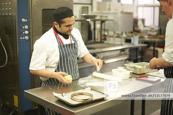 Dozent des Chefkochs demonstriert jugendlichen Gastronomiestudenten Technik an der Küchentheke