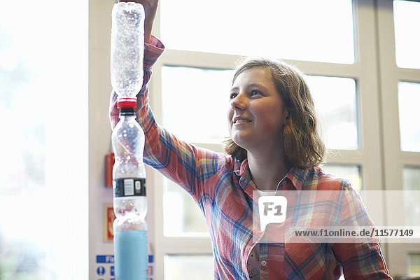 Teenager-Studentin stapelt Plastikflaschen für Experiment im Klassenzimmer