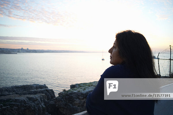Reife Frau schaut in der Abenddämmerung aufs Meer hinaus  Sintra  Portugal