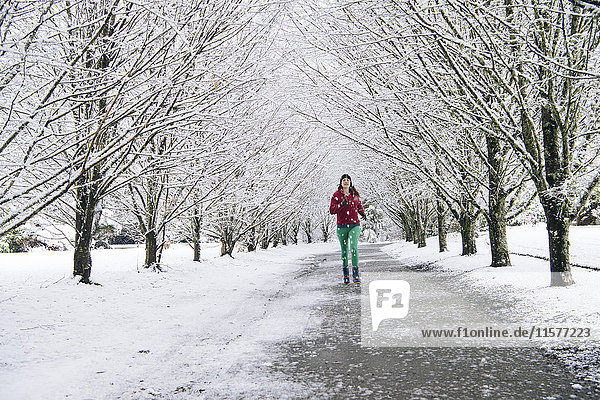 Frau joggt entlang eines Weges  in schneebedeckter ländlicher Umgebung
