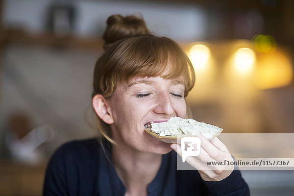 Young woman eating bread with cream cheese