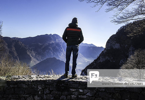 Mann an der Wand stehend  Blick auf den Berg  Rückansicht  Italien