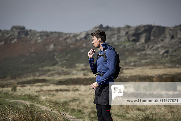 Male runner drinking from tube at Stanage Edge  Peak District  Derbyshire  UK