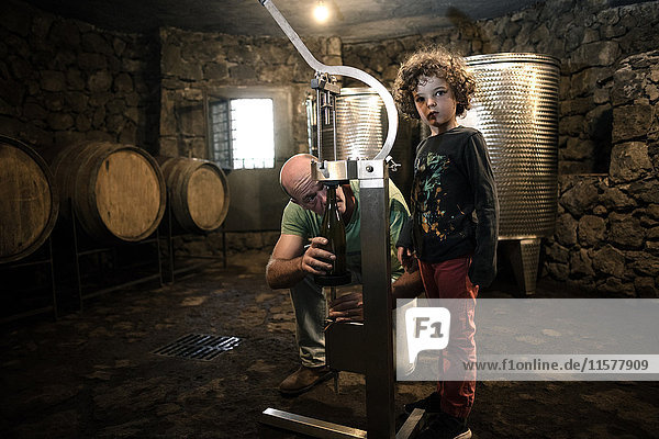 Junge mit Winzer verkorkt Weinflasche im Keller