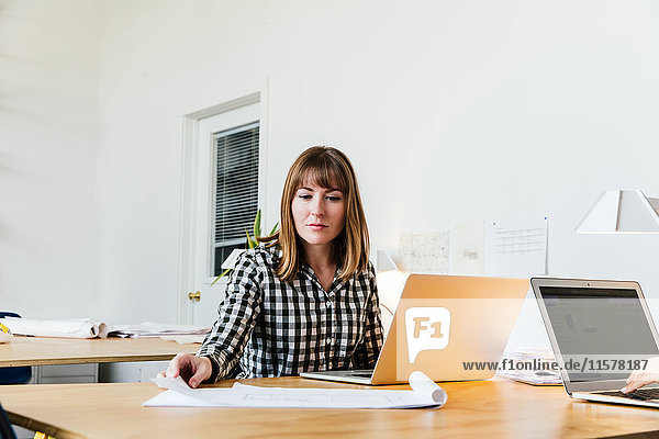 Woman sitting at desk in office working on laptop