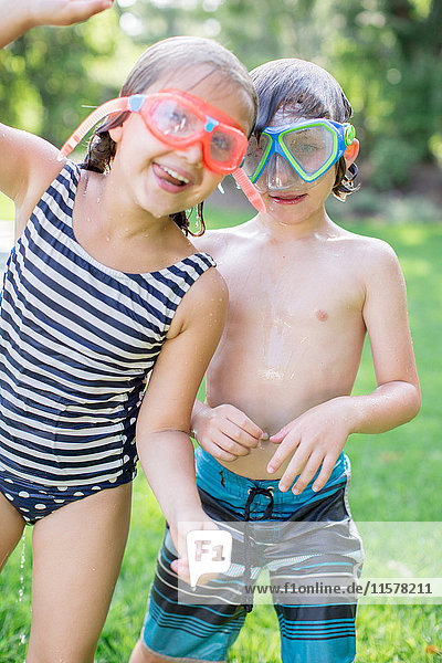 Portrait of boy and girl in garden wearing swimming goggles