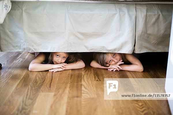 Junge und Mädchen verstecken sich unter dem Bett