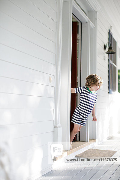 Boy leaning forward from front door onto porch