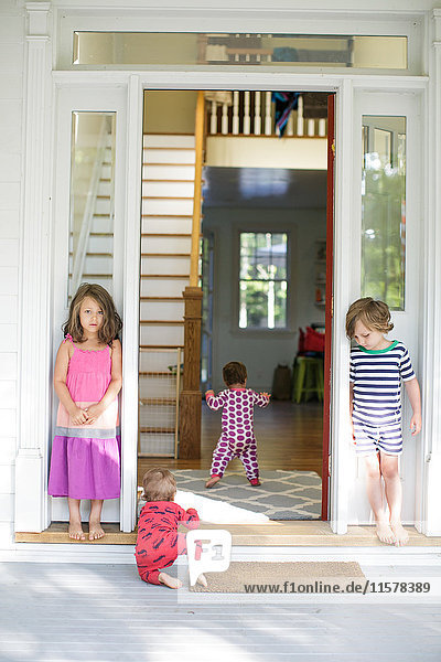 Junge und Mädchen beobachten Kleinkind krabbelnd im Hauseingang