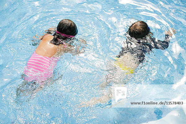 Draufsicht auf einen Jungen und ein Mädchen  die im Freibad schwimmen