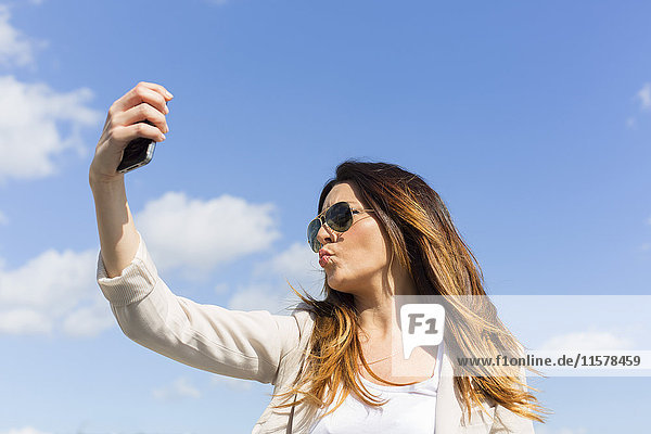 Hübsche brünette Frau beim Selfie mit Smartphone
