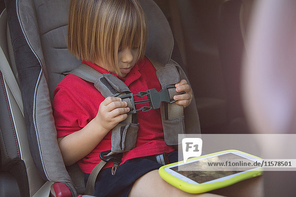 Girl in car safety seat fastening her seat belt