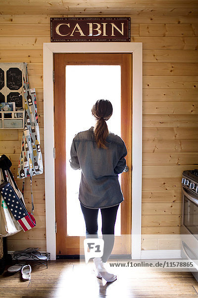 Young woman standing by doorway  looking through window