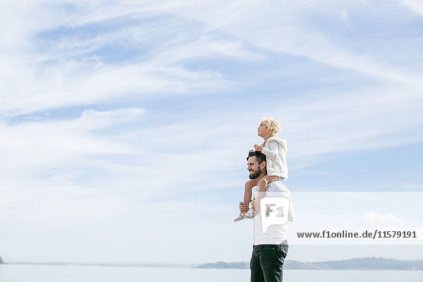 Reifer Mann trägt seine Tochter an der Küste