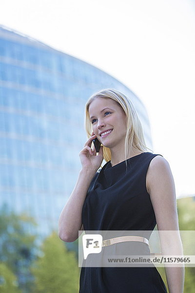 Hübsche  elegante Frau  die vor einem Bürogebäude in der Innenstadt anruft.