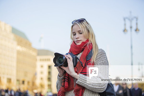Pretty blonde woman with digital camera taking photos in a city in Europe