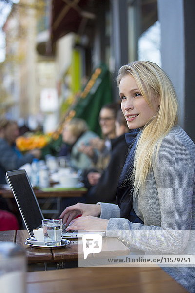 Hübsche nachdenkliche Frau mit Laptop in einem Cafe