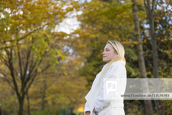 Hübsche blonde Frau mit Mantel im Park im Herbst