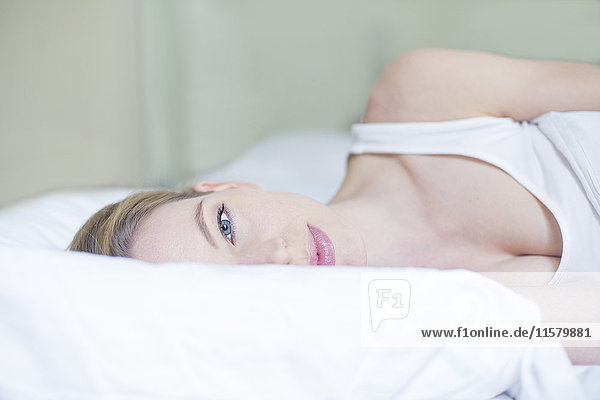 Porträt einer hübschen blonden Frau im Bett mit Blick auf die Kamera